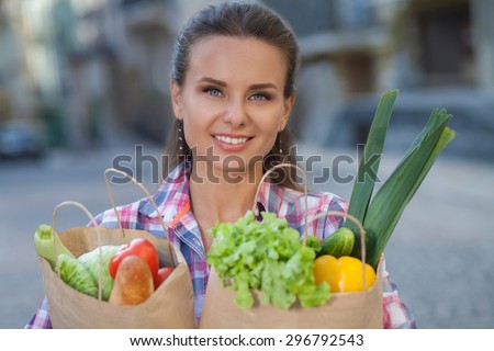 Portrait of pretty woman with bags full of fruits and vegetables. Woman preparing for tomorrow\'s picnic with her best friends.