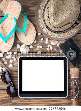 Summer objects for vacation fulfilled the whole picture. THey are flip-flops, straw hat, sunglasses and photocamera isolated on wooden with sea shells and stones.