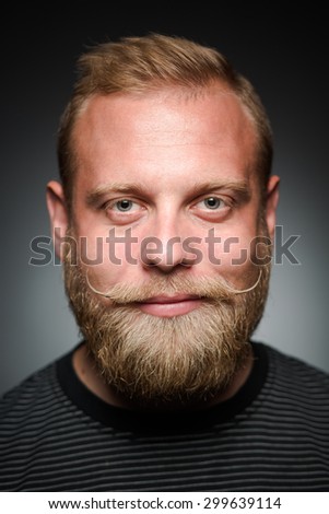 Portrait of happy smiling bearded man on black. Short haired blond man in black T-shirt enjoying his lifestyle.