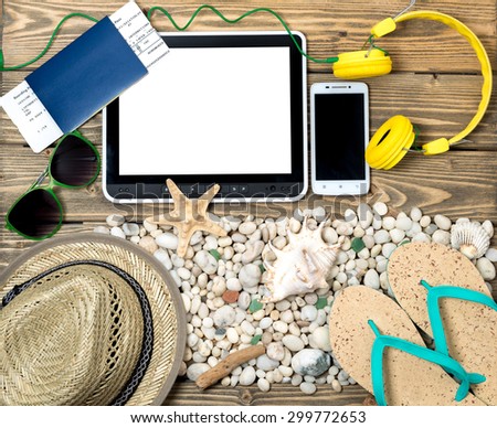 Different objects on and near sea shells and stones ready for summer vacations. Tablet PC is in the center of the picture.