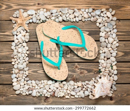 Portrait of flip-flops in the middle of frame from sea shells and stones. All objects onthe picture ozranized on wooden and respresent summer.