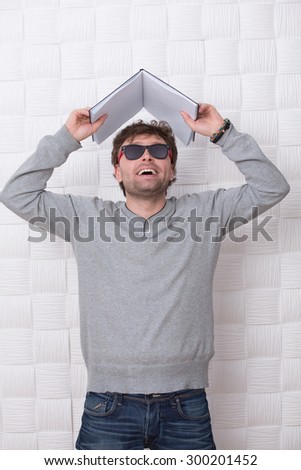 Portrait of handsome man posing with register above his head. Man in sunglasses looking upwards and showing his emotions because of happiness.