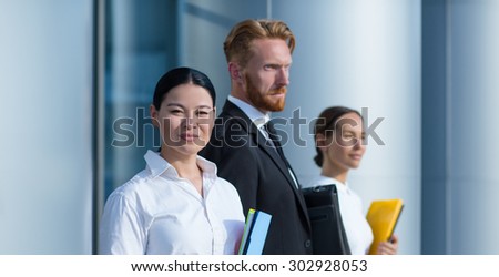 Close-up portrait of successful asian businesswoman isolated on her collegues over background. Woman in white shirt smiling with folder in her hands.