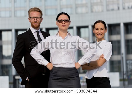 Group of happy business people with businesswoman leader on foreground. Woman in sunglasses posing with her arms akimbo.
