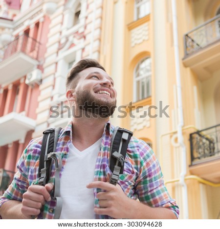 Close-up picture of smiling handsome man in the city. Short-haired bearded man with backpack happy smiling.