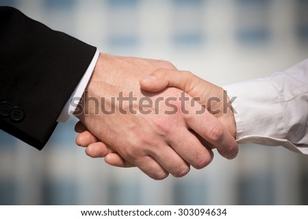 Business handshake on bright background. Photo of handshake of business partners after signing promising contract.