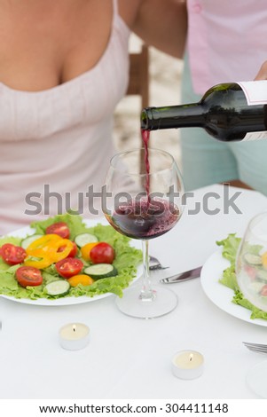 Sommelier pouring red wine in the galss. Man pouring the red wine for beautiful woman in the restaurant.