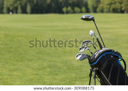 Golf clubs over green field background. Bunch of golf clubs in the bag ready to be used for playing professional golf and having nice vacation in summer.