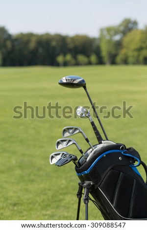 Golf club against the background of green field. Golf organizer cart bag with golf clubs. It is nice idea to spend your vacation during summer time.