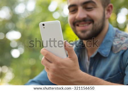 Close-up portrait of happy man reading messages on the smart phone. Hipster man using mobile phone for business goals.