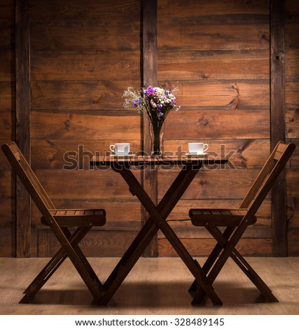Beautiful wooden table for two persons to have a date in romantic atmosphere and drink a tasteful coffee or tea.