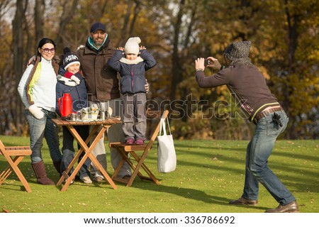Family and picnic concepts. Young family spending free time on a picnic with friends. Man making photos of a whole family in the park.