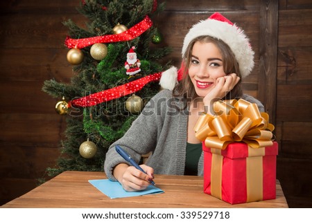 Happy beautiful girl smiling and thinking about New Year and Christmas congratulation to write to her relatives or friends abroad.