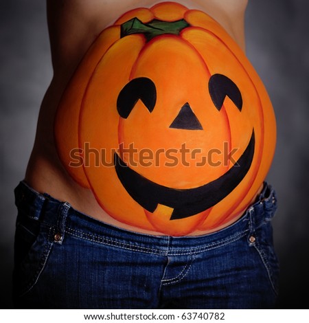 Halloween pumpkin painted on belly of pregnant woman