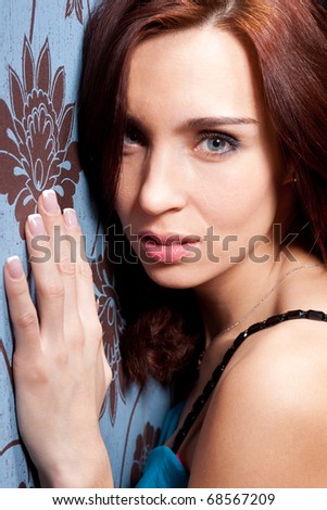 Close up portrait of beautiful girl, that stay near wall with blue wallpapers