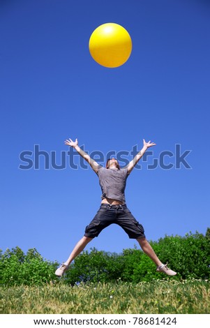 Young man jump in park with yellow ball