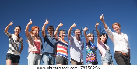 Group of people raise hands in air across blue sky