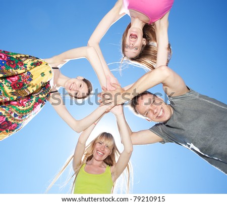 Group of young people hug each other across blue sky