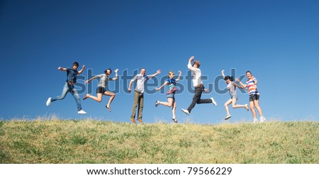 Group of people jump on hill across blue sky