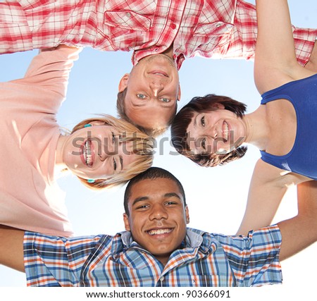 Group of young people outdoor hug each other across blue sky