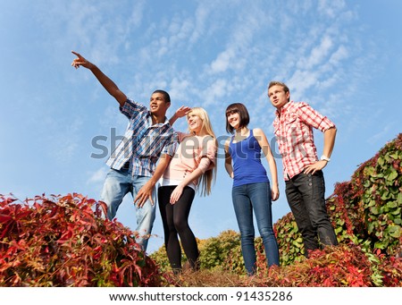 Group of young people outdoor rise up hands across blue sky