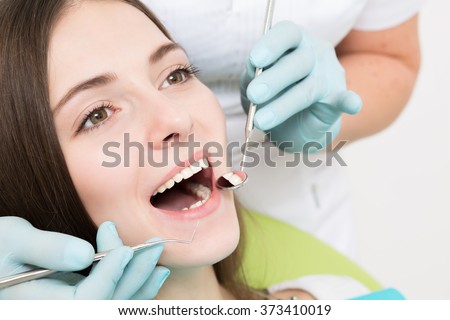 Close-up picture of young woman sitting in the dentist\'s chair with opened mouth at dentist\'s office while having examination.
