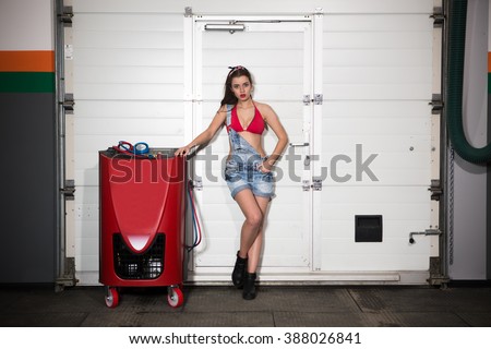 Happy lady posing near professional air conditioning stations for cars over white background in repair shop. Happy smiling woman in jeans shorts and red underwear.