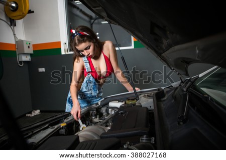 Mechanic woman repairing motor or electric parts of car in garage. Beautiful lady working at service station.