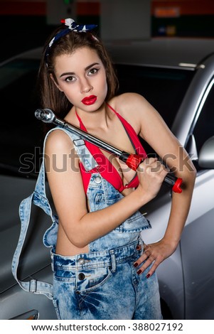 Beautiful young female auto garage manager portrait inside workshop. Pretty lady with red lips looking at camera at station service.