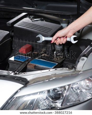 Woman mechanic tuning car with diagnostic equipment. Lady holding wrench to solve problem at service station.