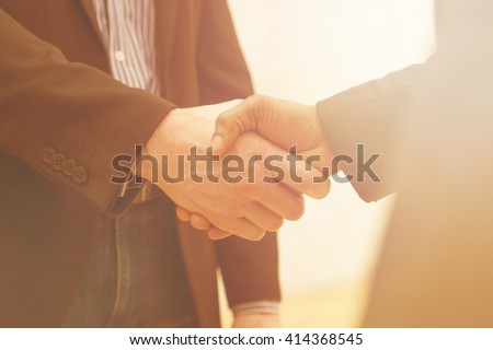 Business handshake of two men demonstrating their agreement to sign agreement or contract between their firms / companies / enterprises.