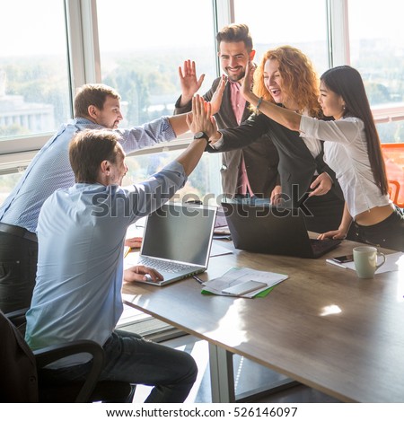 Business people giving five to their colleague after dealing with foreign partners and signing contract or agreement between companies, enterprises or firms. Teamwork concept.