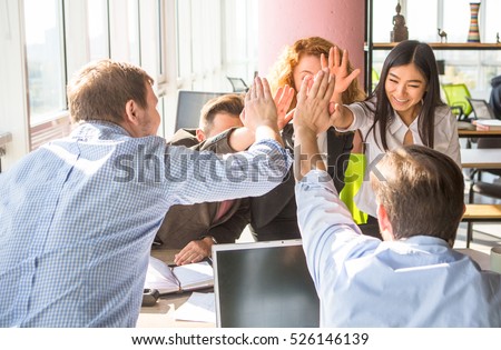 Business people happy showing team work and giving five after signing agreement or contract with foreign partners in office interior. Happy people smiling. Agreement or contract concept.