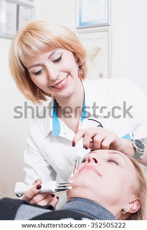 beautiful girl beautician making permanent makeup on woman\'s face. Blonde. doctor