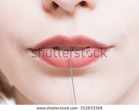 painted lips girl. needle from the syringe is pressed against the lips. Botox.
