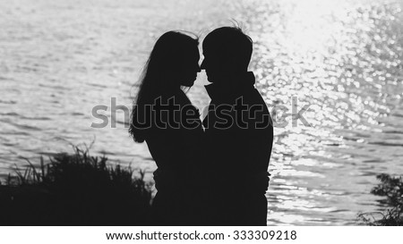couple in love hugging by the water, the silhouette