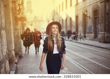 Portrait of young beautiful woman wearing hat walking in the old city. Street fashion concept. Toned
