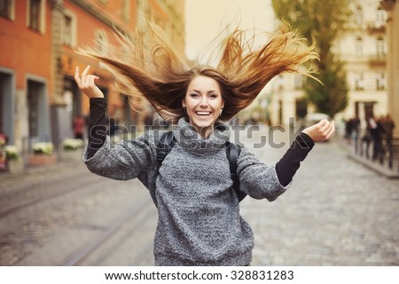 Happy young smiling woman playing with her long beautiful hair. Emotional portrait