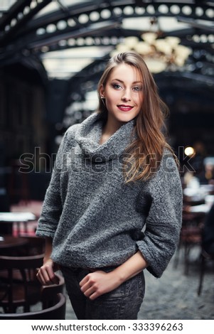 Young woman in a knitted turtleneck sweater smiling and looking at camera.