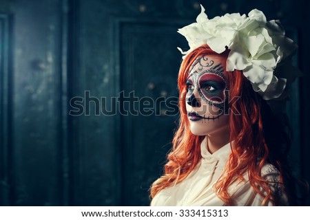 Portrait of beautiful young redhead woman with Halloween sugar skull makeup looking aside. Close up. Dark green backgraund. Copy space, free text.
