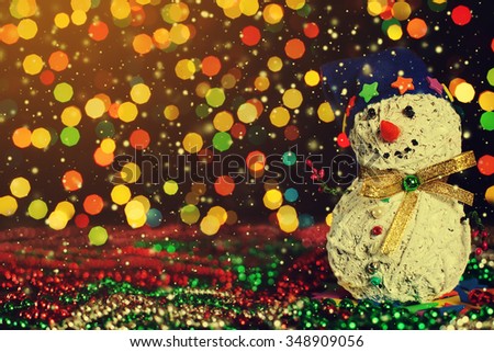 Christmas decorative handmade snowman on the garland lights background.  Magic snowfall in lantern light. Closeup. Selective focus. Copy space