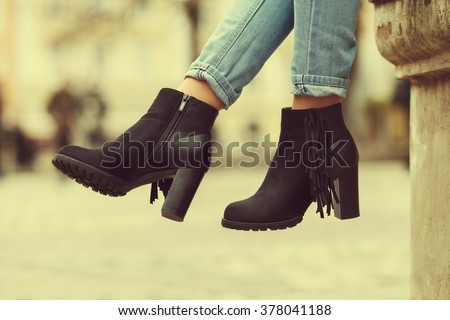 Elegant outfit. Closeup of stylish black suede ankle boots. Fashionable girl on the street. City lifestyle. Female fashion. Toned