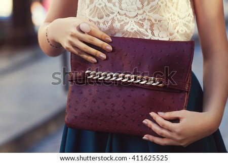 Elegant outfit. Closeup of leather bag in hands of stylish woman. Fashionable girl on the street. Female fashion. City lifestyle. Toned