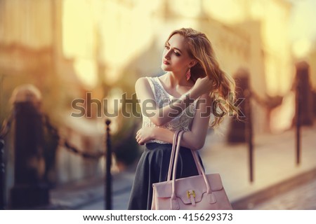 Outdoor portrait of a young beautiful fashionable lady walking on street. Model wearing stylish clothes. Girl looking aside. Female fashion. City lifestyle. Toned style instagram filters