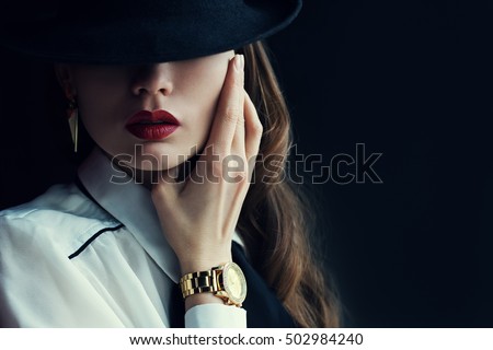 Indoor portrait of a young beautiful  fashionable woman wearing stylish accessories. Hidden eyes with hat. Female fashion, beauty and advertisement concept. Close up. Copy space for text