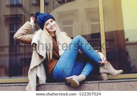 Outdoor full body portrait of young beautiful happy smiling girl posing on street. Model looking at camera. Lady wearing stylish winter clothes. Female fashion. Toned
