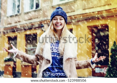Young beautiful happy smiling girl acting thrilled, wearing stylish clothes. Model expressing joy and excitement with hands and face. Snowfall. Christmas, new year, winter holidays concept. Waist up
