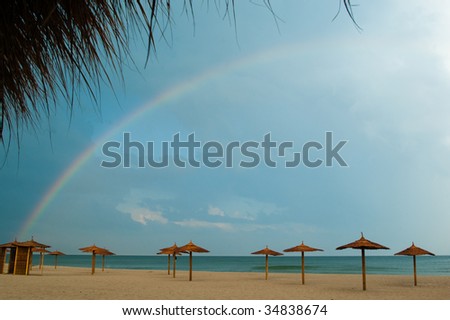 Rainbow over the beach with wooden sun covers