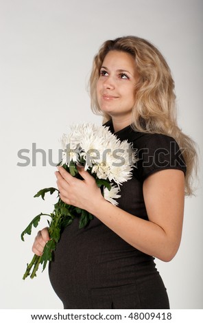 Beautiful young seven-month-pregnant woman in black dress with white flowers smiling
