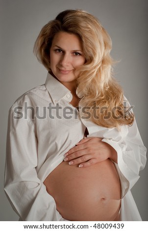 Beautiful young blond woman seven-month pregnant in a white men\'s shirt